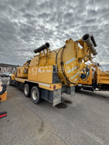 International vacuum truck 2008 model with large cylindrical vacuum tank mounted on a dual rear-axle trailer, yellow equipment, hoses and exhaust stacks visible.