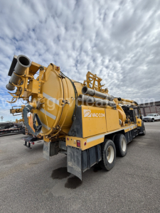 International vacuum truck showing large yellow sludge pump and hoses, with VACCON branding on the side and rear view.