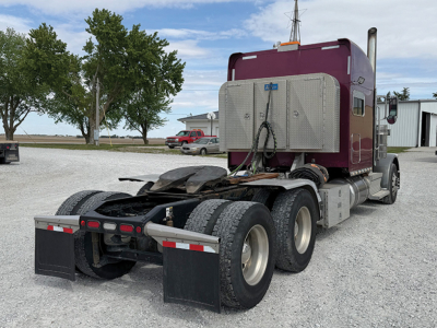 Peterbilt 389 UltraCab rear view showing tractor chassis and dual rear axles under a maroon cab with wind deflector and chrome fuel tanks.