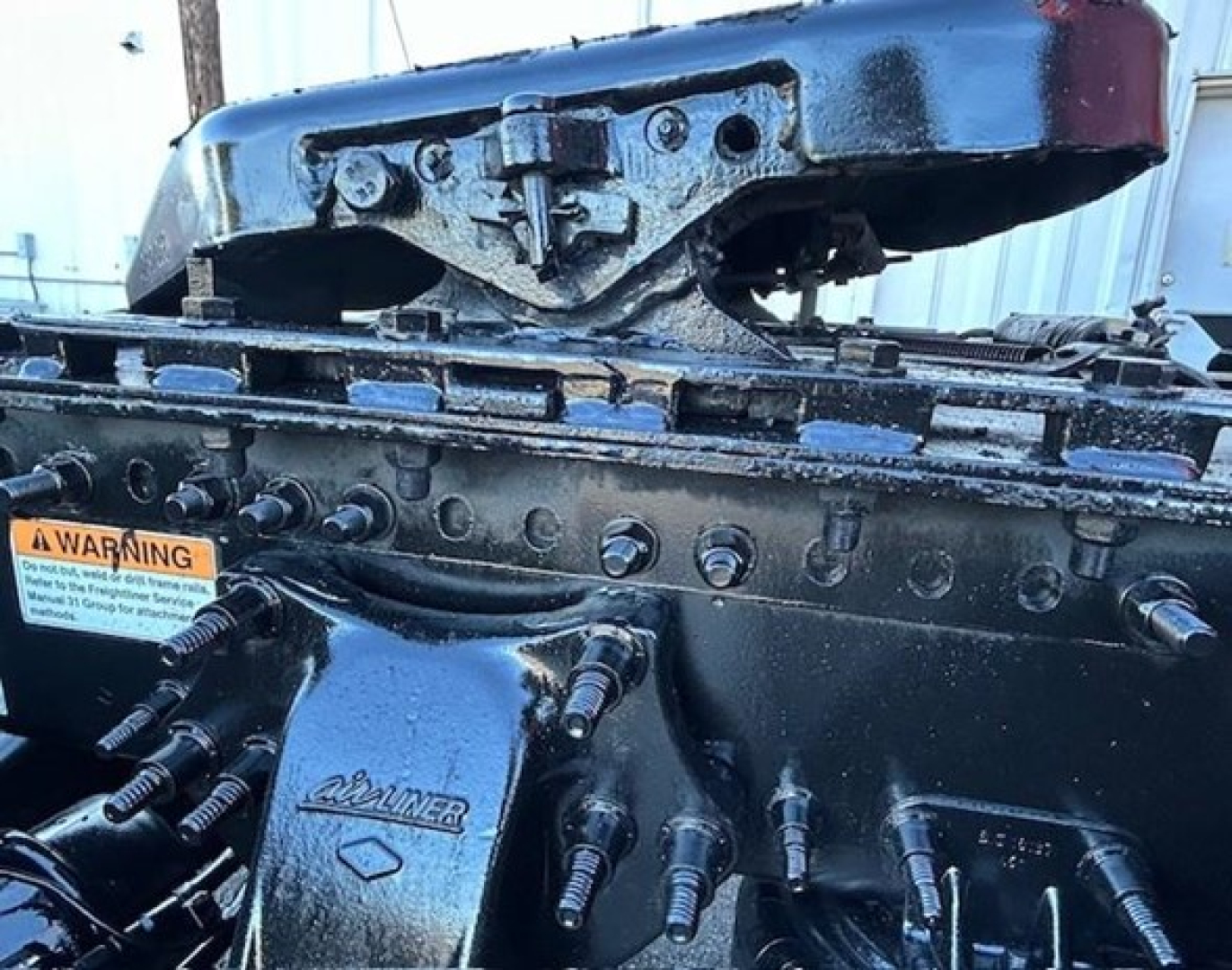 Truck engine bay components showing valve covers and engine block with multiple hoses and bolts; warning sticker visible.
