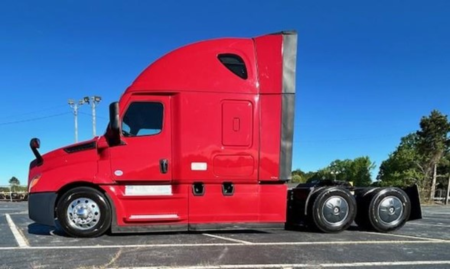Red Freightliner Cascadia 126 tractor-trailer side view showing sleeper cab and dual rear axles.