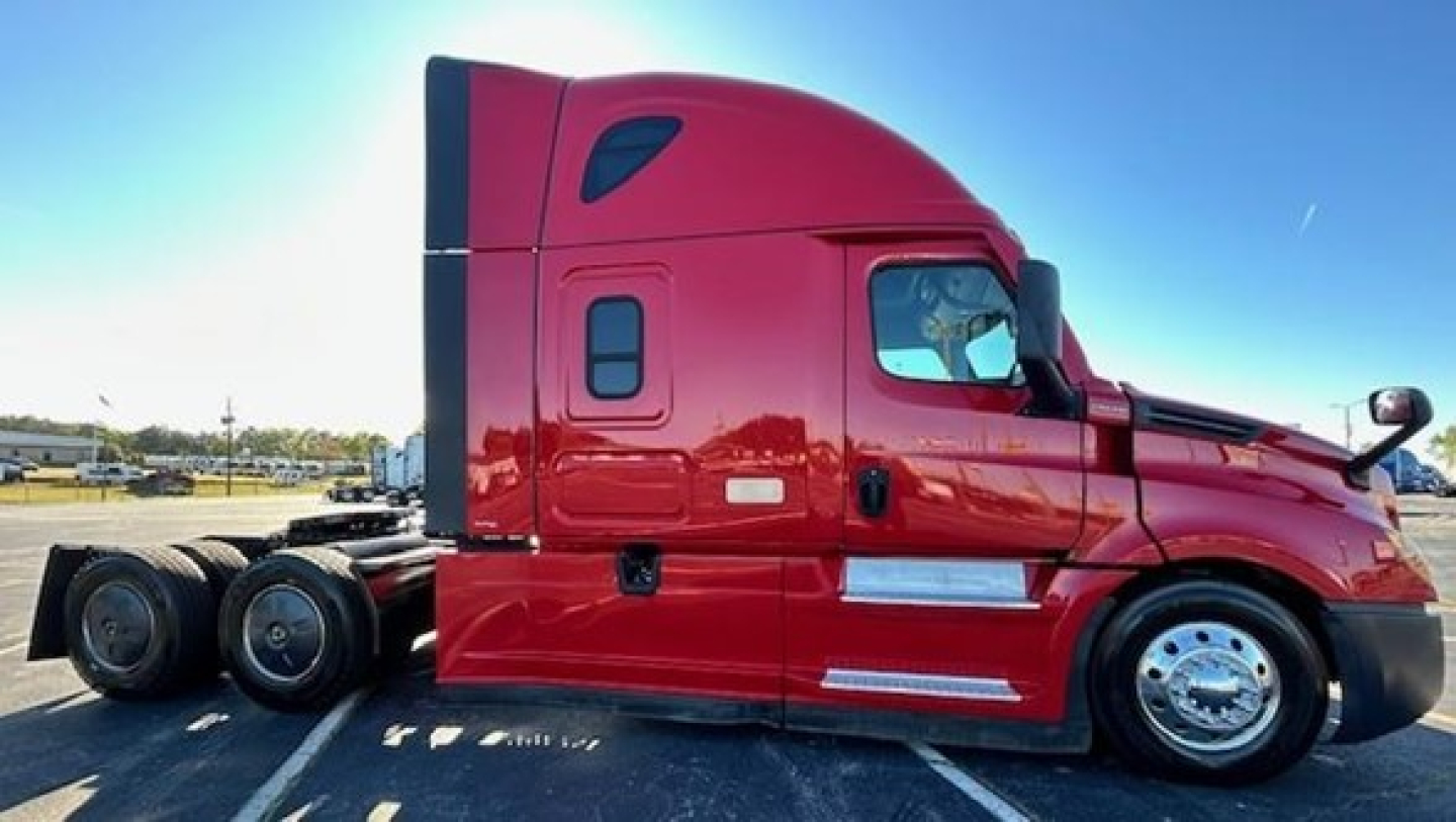 Freightliner Cascadia 126 sleeper tractor in red side view showing cab and dual rear axles.
