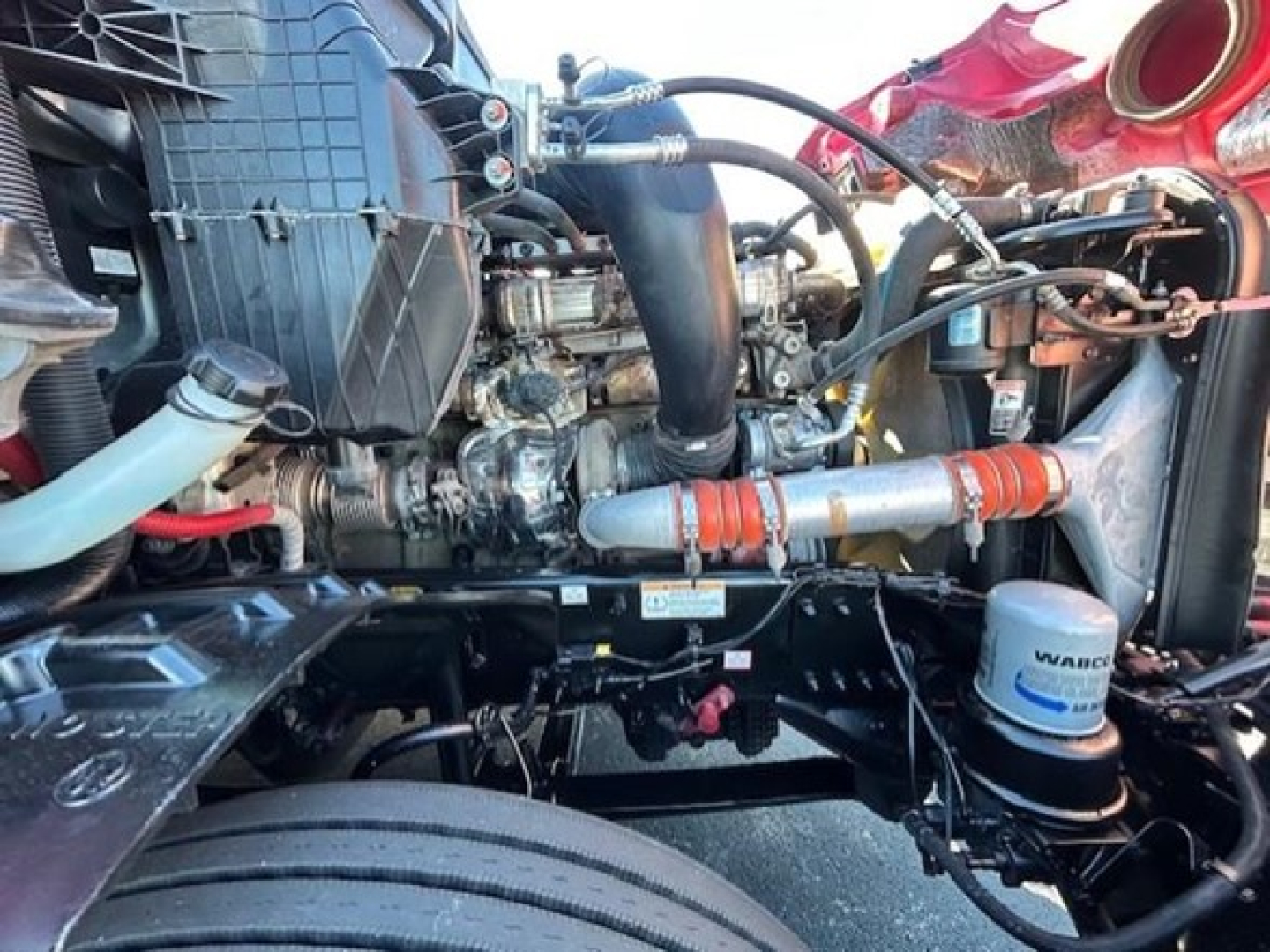 Freightliner Cascadia engine bay with visible hoses, turbo, intake, coolant and filter canister in view.