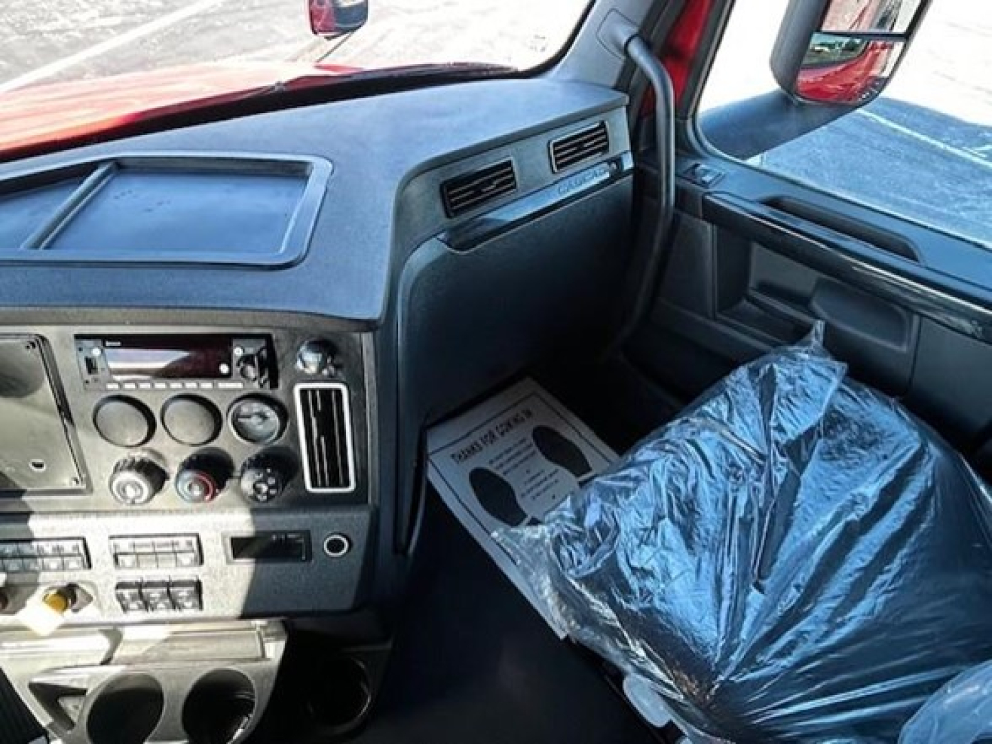 Cab interior of a Freightliner Cascadia truck showing dashboard controls and steering area.