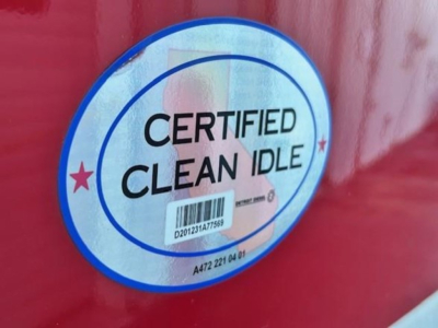Circular sticker on red vehicle showing 'CERTIFIED CLEAN IDLE' with barcode and small stars.