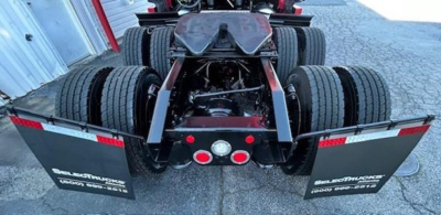 Rear view of a Freightliner Cascadia 126 truck chassis showing dual rear axles and mudflaps with Freightliner branding.