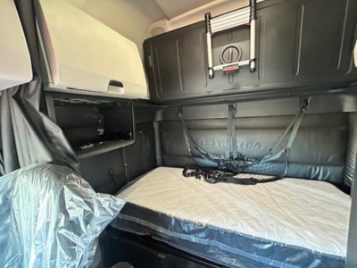 Freightliner Cascadia 126 sleeper cab interior showing bed with mattress, overhead storage, and mounting hooks.