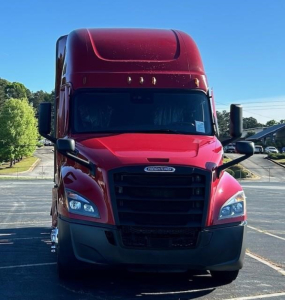 Freightliner Cascadia 126 front view showing bold black grille, red cab with large windshield, headlights, and side mirrors.