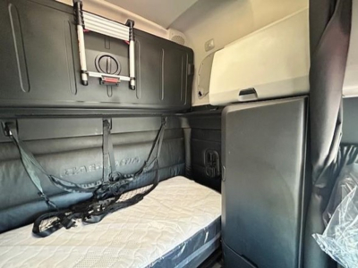 Freightliner Cascadia 126 sleeper cab interior showing bunk bed with mattress and overhead storage compartment.