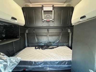 Freightliner Cascadia 126 sleeper cab interior cargo bed with rear wall and straps, bare mattress visible.