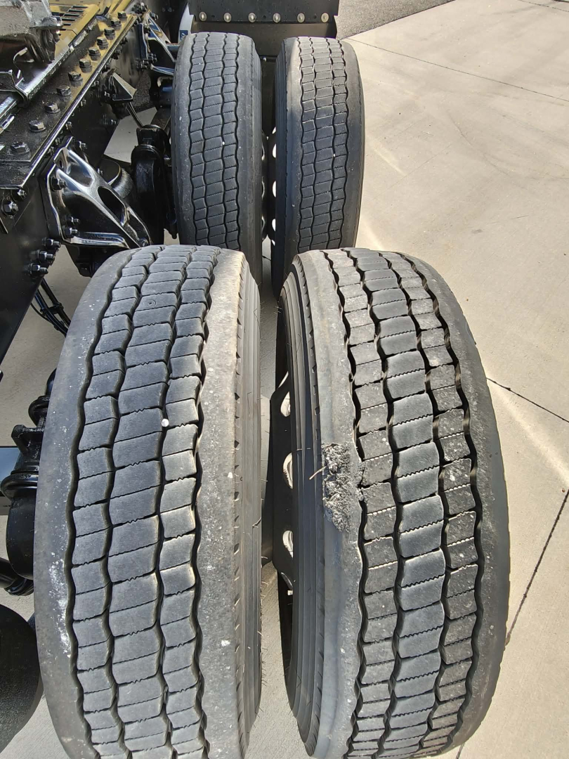 Kenworth T680 rear axle area showing dual rear wheels with tread on tires and undercarriage components