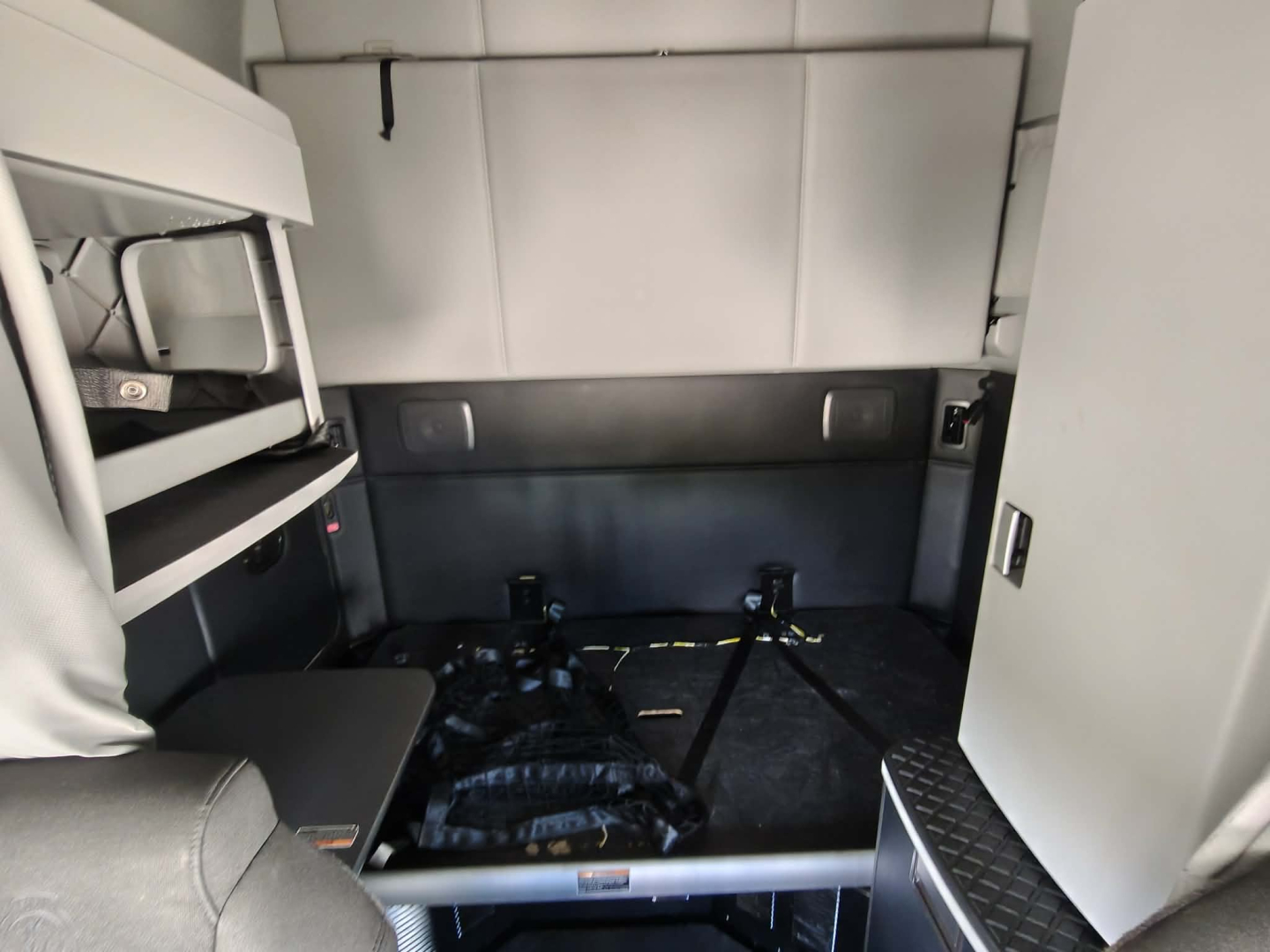 Kenworth truck cab interior showing sleeper area with bed and storage cabinets.