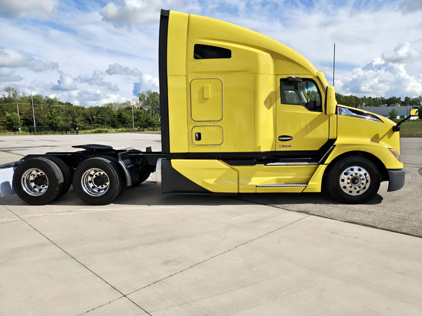 Yellow Kenworth truck in profile view with sleeper cab and dual rear axles, no visible text on side