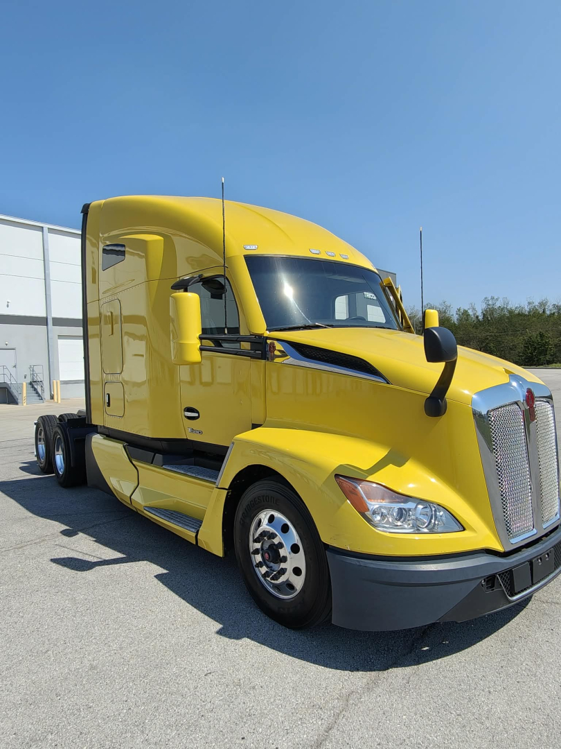 Kenworth T680 tractor in yellow, front-left view showing sleeper cab, chrome grille, aerodynamic mirrors, and daytime running lights.