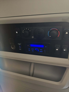 Dashboard controls of a Kenworth T680 cab showing climate controls, radio head unit, and storage pocket.