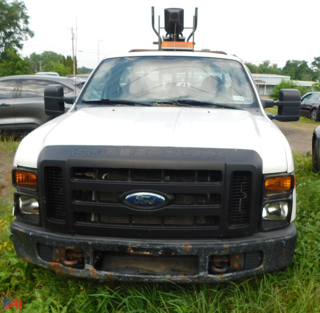 Ford F-250 Super Duty front view with utility box and roof equipment, white cab, black grille, and bumper with rust spots.