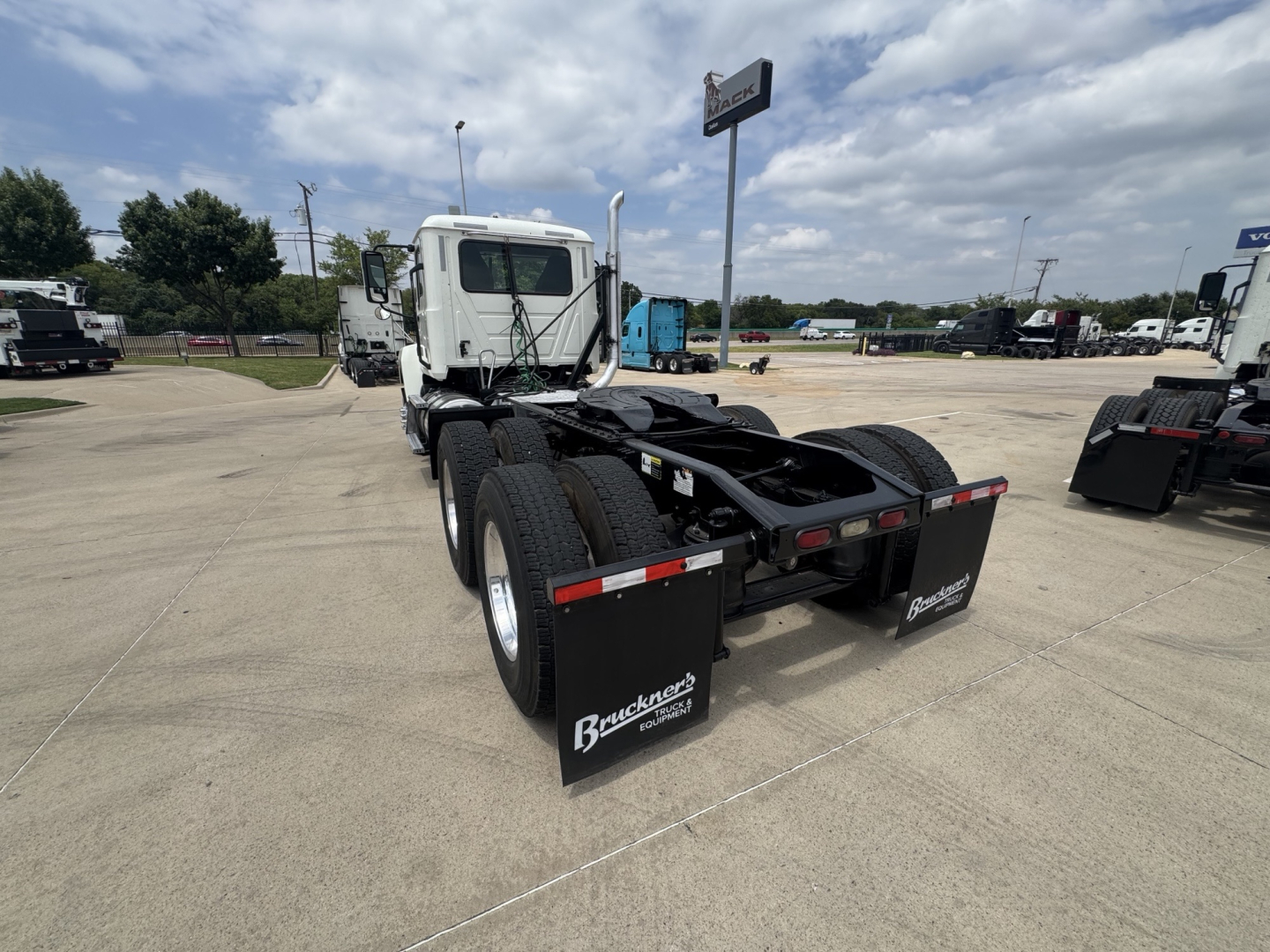 Truck chassis with dual rear axles and fifth wheel seen from rear-left in a dealership lot