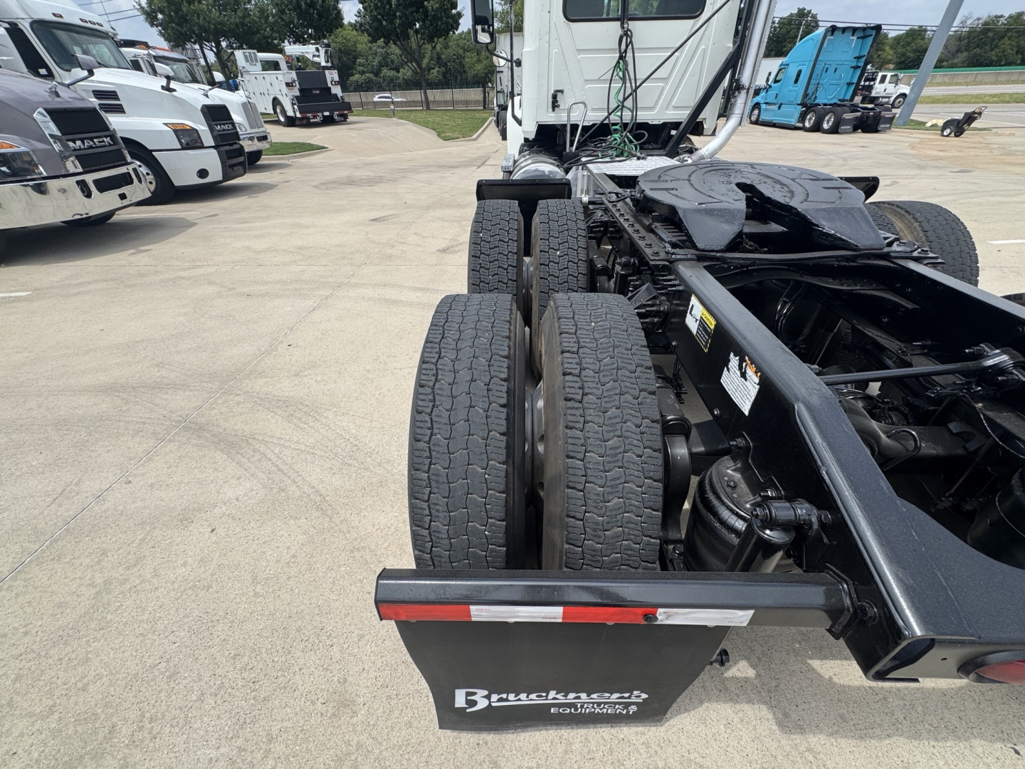 Rear view of a 2020 Mack PI64T tractor chassis showing dual rear axles and trailer hitch area with Brackett-braker? brand plate on mudguard.