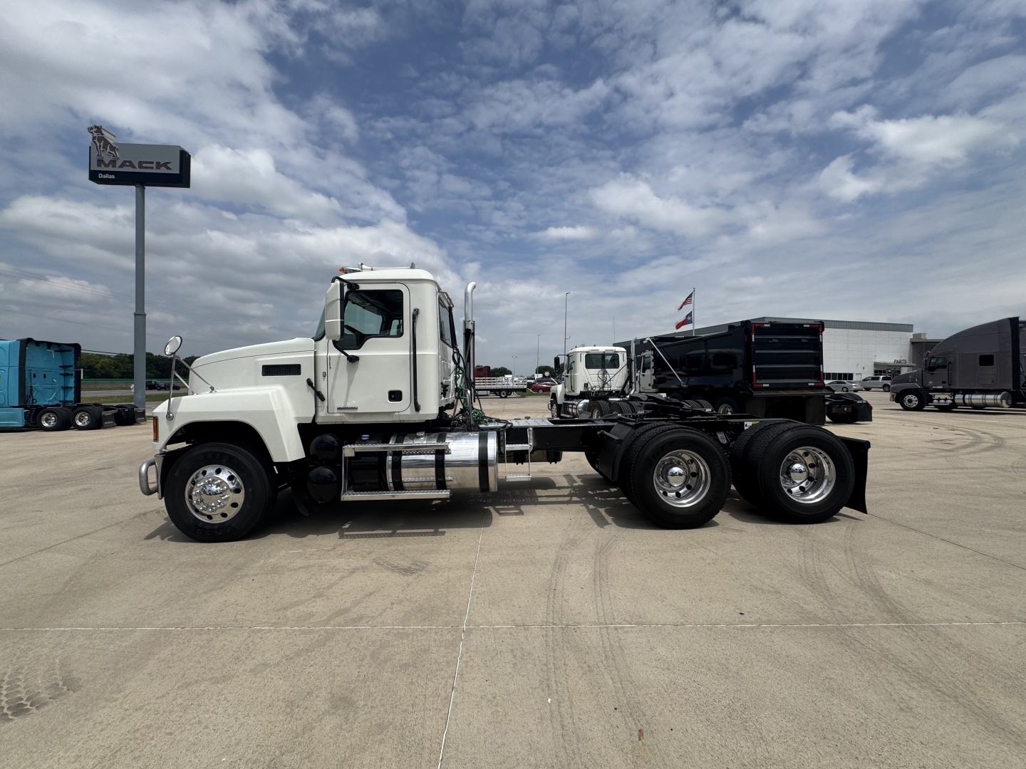 Mack PI64T truck in side view showing cab, fuel tanks, and dual rear axles on a concrete lot.