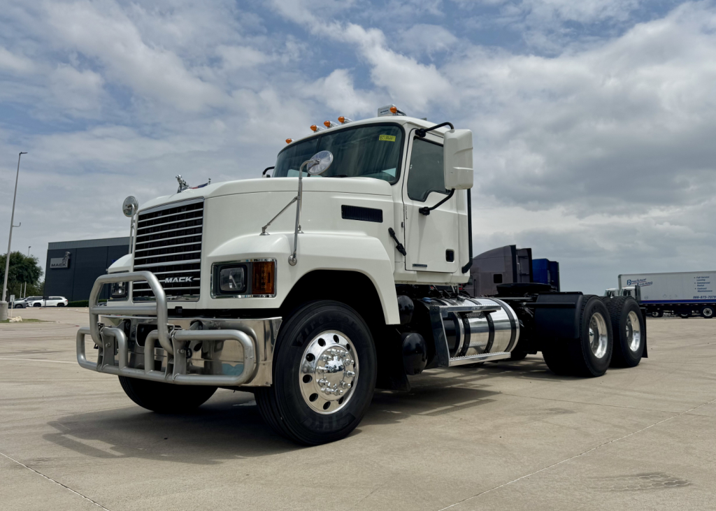 Truck: 2020 Mack PI64T conventional daycab front-left view showing chrome bumper, grille, large side mirrors, fuel tanks, and dual rear axles.