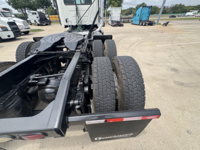 Tractor-trailer chassis of a 2020 Mack PI64T daycab showing rear dual drive tires and frame with fifth wheel mounting in a lot.