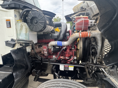 Mack PI64T engine bay showing coolant reservoir, intercooler piping, turbo, coolant hoses, and engine block with red paint; various hoses and component reservoirs visible.