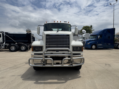 Front view of a white 2020 Mack PI64T daycab truck with a heavy-duty bumper guard in a dealership lot.