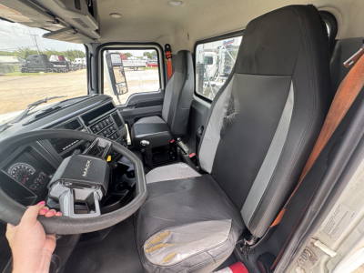 Interior of a 2020 Mack PI64T truck cab showing steering wheel, driver seat with wear, passenger seat, and dashboard. Steering column and gear selector visible.