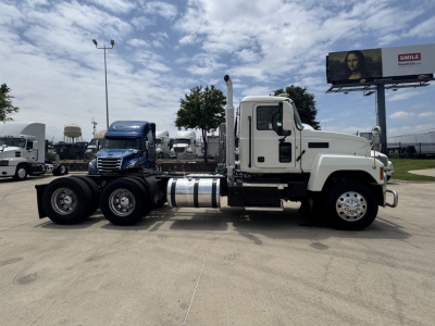 Truck side view of a 2020 Mack PI64T conventional daycab showing white cab, dual rear axles, chrome fuel tanks, and black exhaust stack.