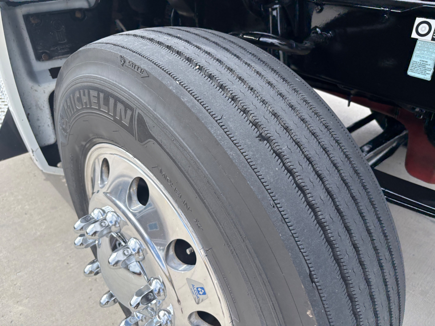 Truck wheel and tire assembly with Michelin tire and rim; portion of chassis and fender visible.