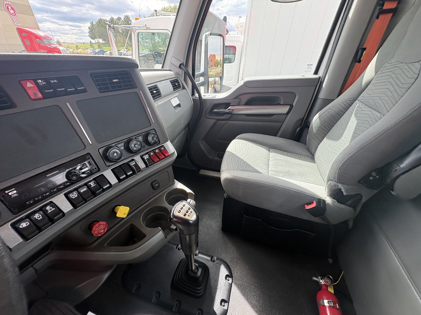 Truck cab interior showing steering wheel, dashboard, gear shifter, and front passenger seat in a 2019 Kenworth T880.