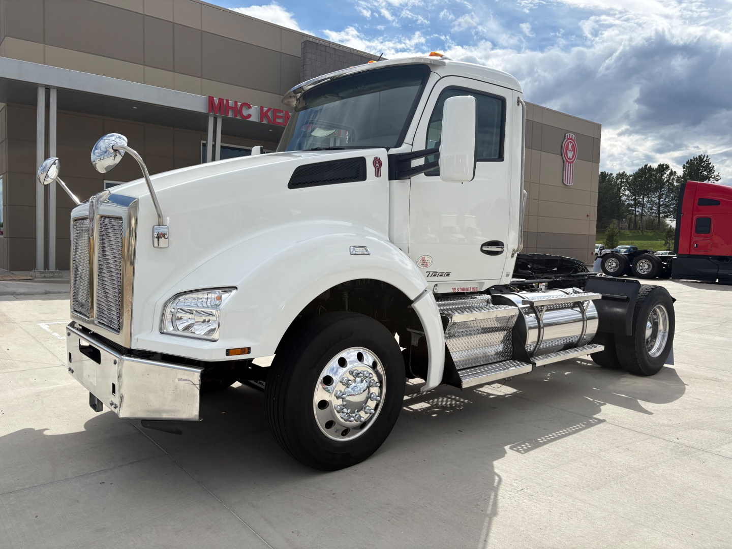 Kenworth T880 conventional daycab truck in white, side view showing chrome fuel tanks, steps, and dual rear axles.