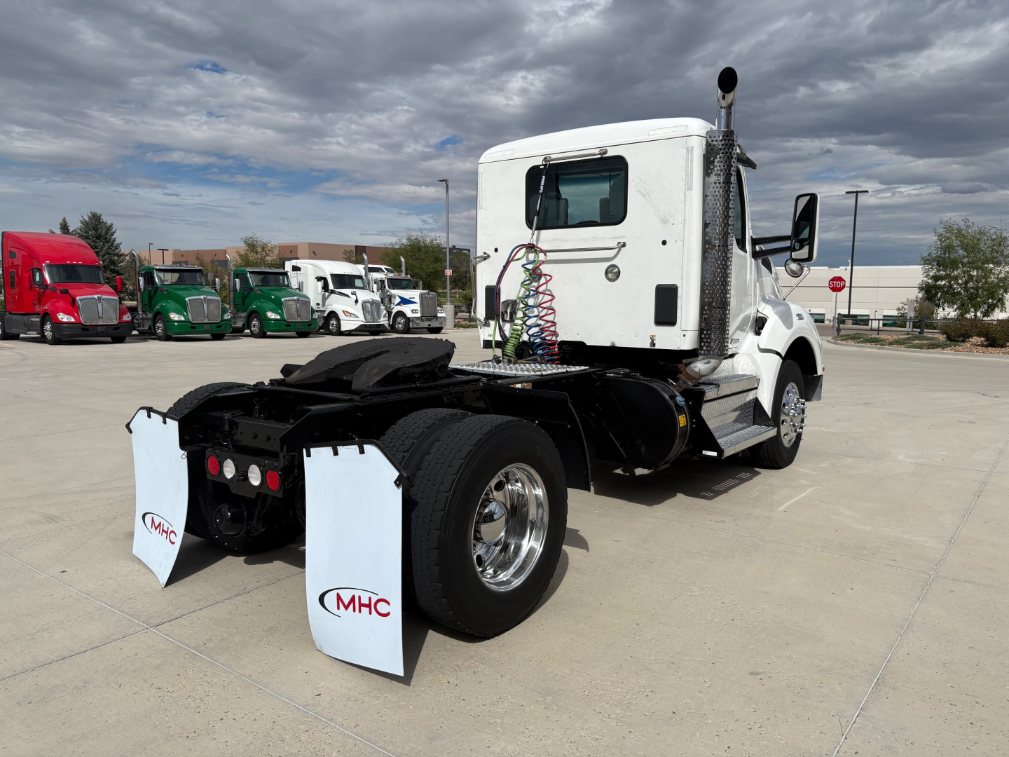 Truck chassis of a white 2019 Kenworth T880 conventional daycab seen from rear-left, with dual rear axles, spare mud flaps labeled MHC, and fifth-wheel area visible.
