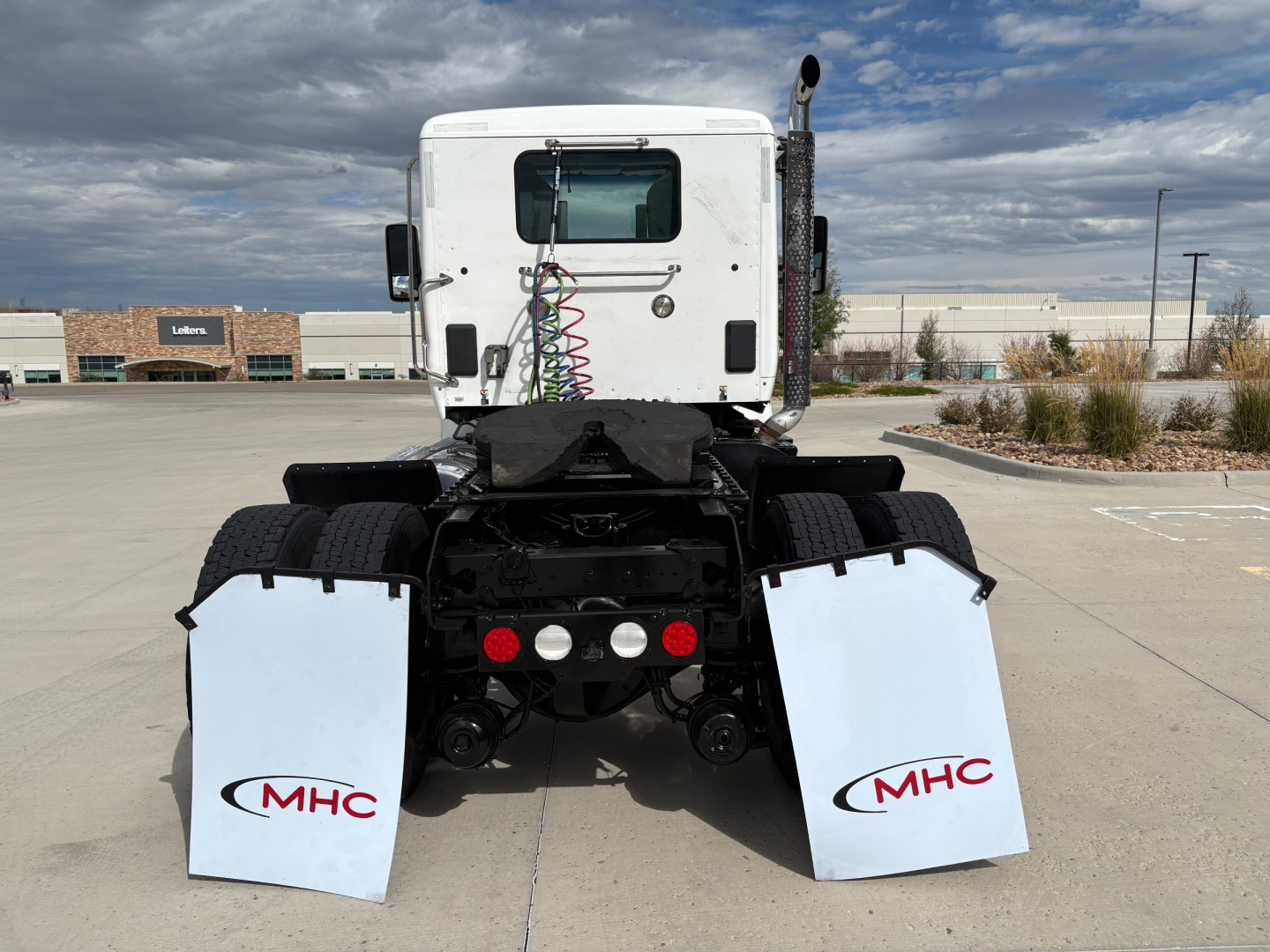 AWD Kenworth T880 tractor rear view showing mud flaps with MHC logos and fifth-wheel area.