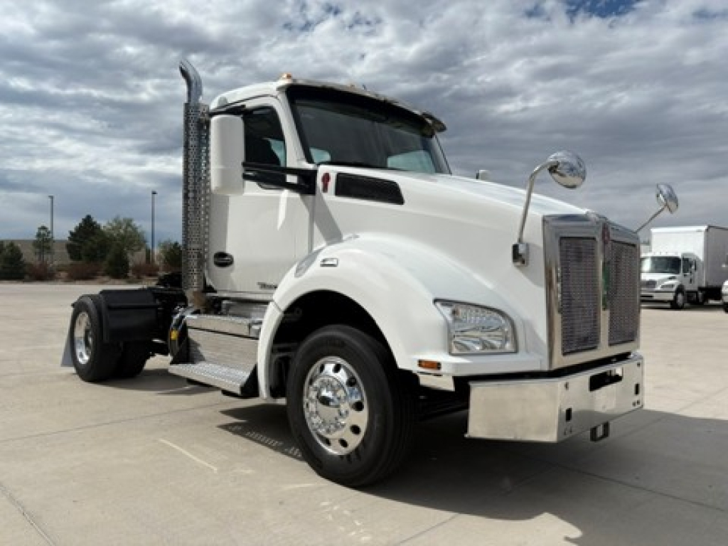 Kenworth T880 conventional daycab truck in white, front-left view showing cab, chrome grille, vertical exhaust stack, side mirrors, and fuel tanks.