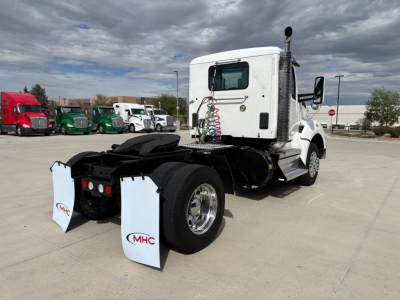 Truck chassis of a white 2019 Kenworth T880 conventional daycab seen from rear-left, with dual rear axles, spare mud flaps labeled MHC, and fifth-wheel area visible.