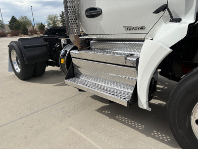 Kenworth T880 side view showing chrome diamond plate fuel/steps with T880 badge on cab and wheel well, front chassis and dual rear tires visible.