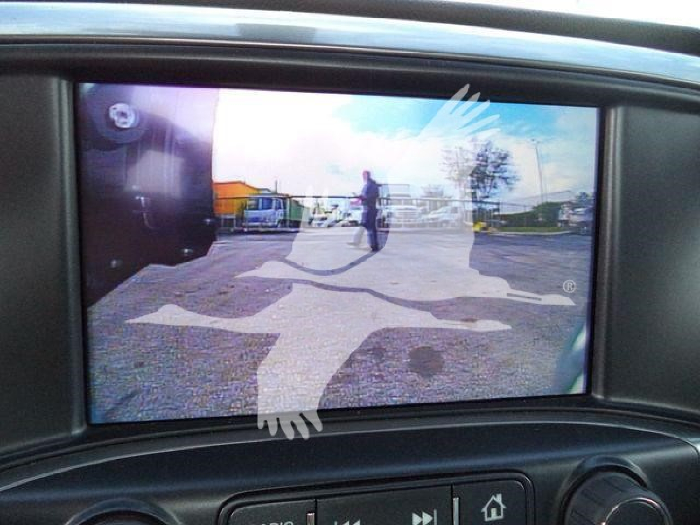 Dashboard screen showing a reflective backup camera view with a large white decal of a jumping horse.