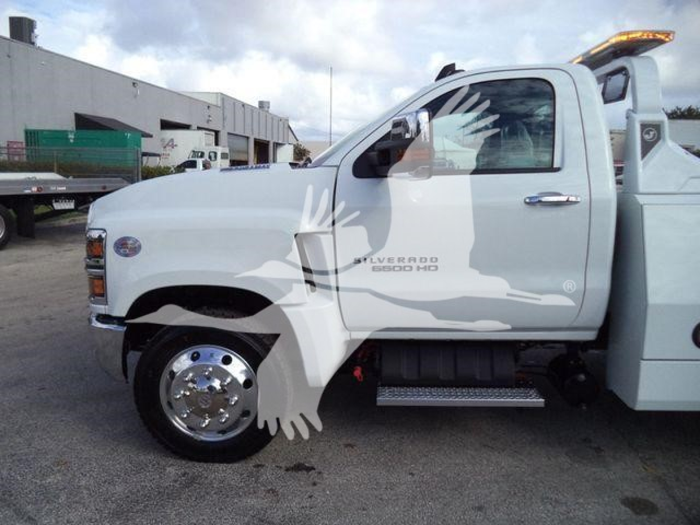 Truck side view showing Chevrolet Silverado 6500 HD badge and wheel, with winch equipment on a white cab chassis.