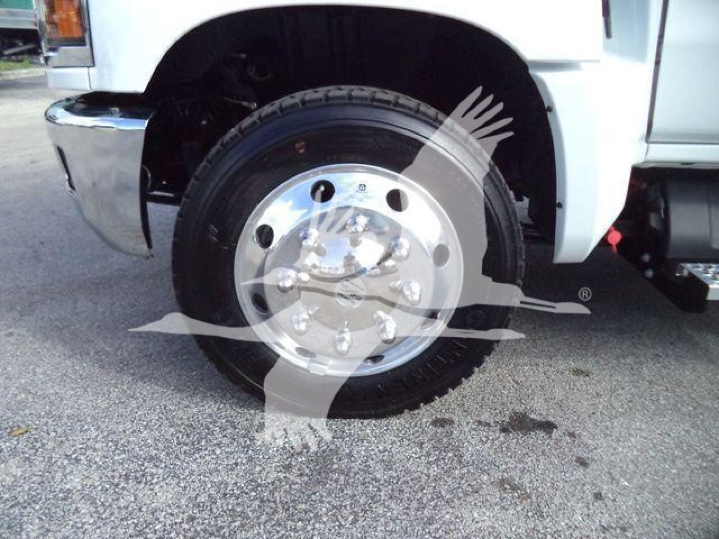 Truck wheel with chrome hubcap and tire on Silverado 6500HD front fender area, showing wheel and part of chassis.
