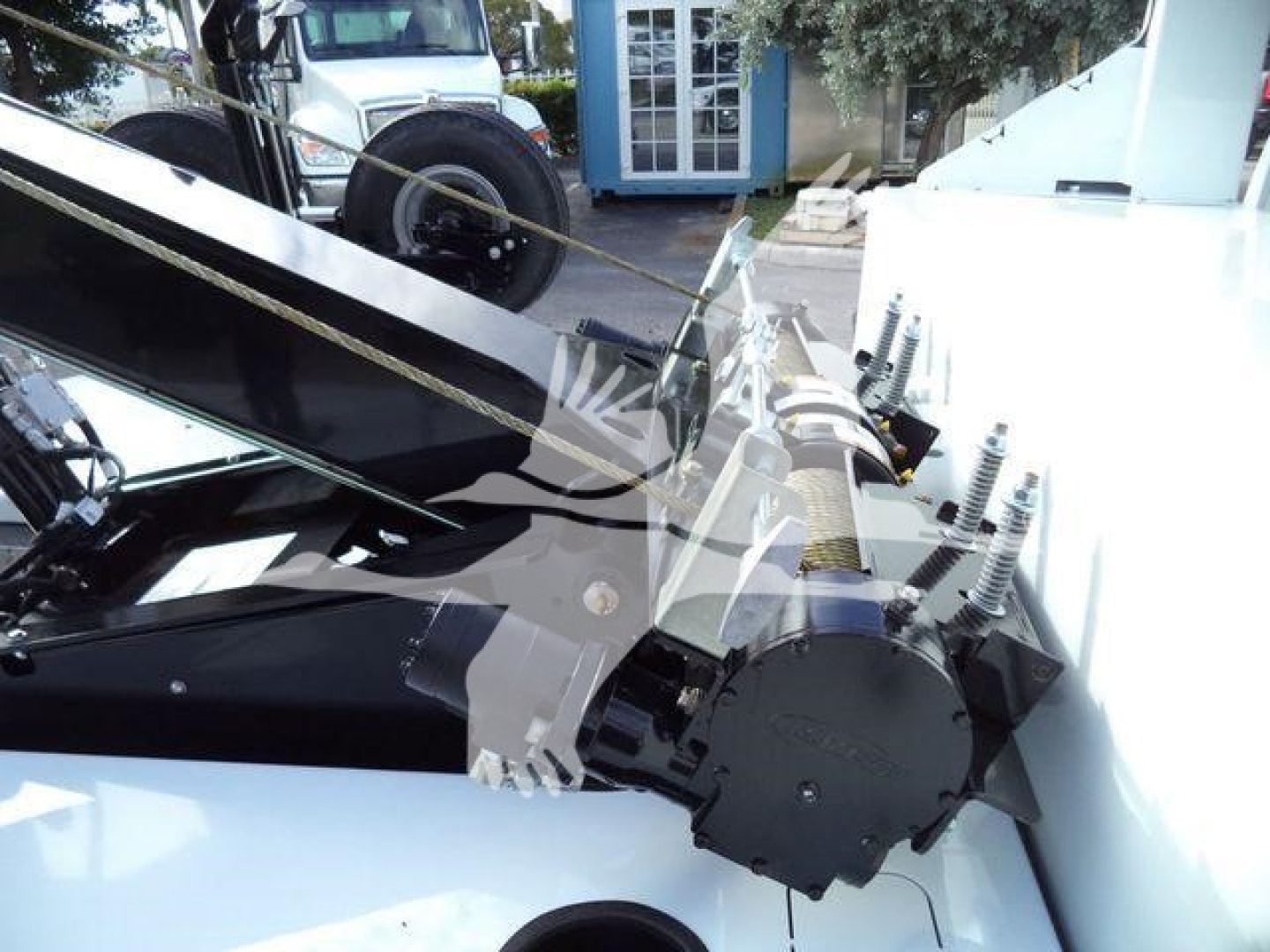 Winch assembly on a Silverado 6500HD truck showing hydraulic winch motor and gears with mounting brackets and control cables.