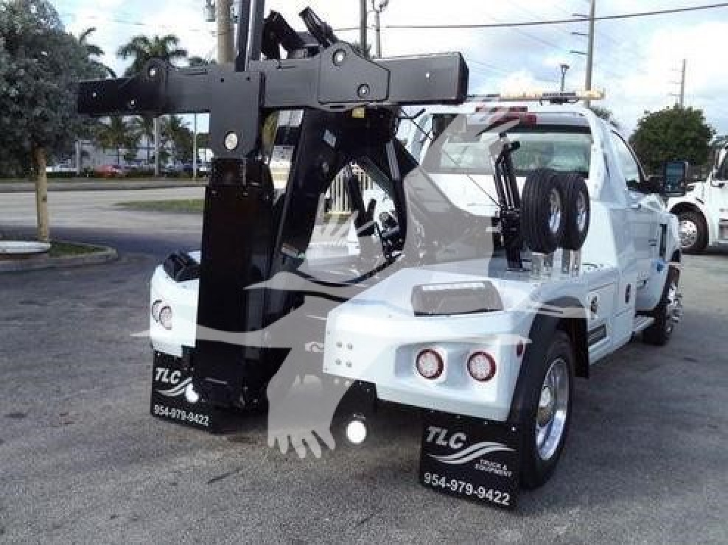 Truck with heavy-duty tow winch and hoist equipment mounted on a white pickup bed, front bumper and winch hook visible.