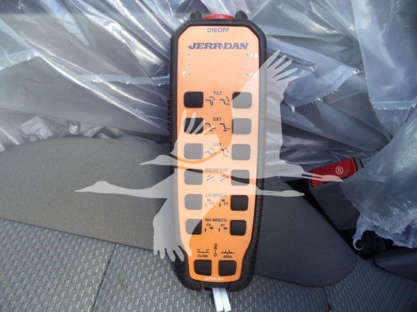 Remote control panel for a Jerr-Dan winch showing labeled switches and indicators on an orange panel.