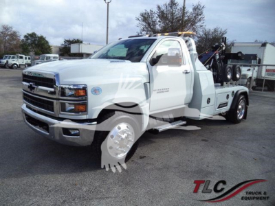 Truck image showing a white 2023 Chevrolet Silverado 6500HD tow truck with a wheel-lift bed, winch system, and towing equipment.
