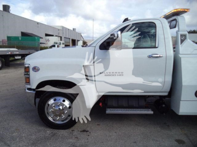 Truck side view showing Chevrolet Silverado 6500 HD badge and wheel, with winch equipment on a white cab chassis.