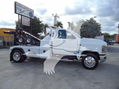 Truck side view of 2023 Chevrolet Silverado 6500HD tow truck with winch bed showing equipment and branding.