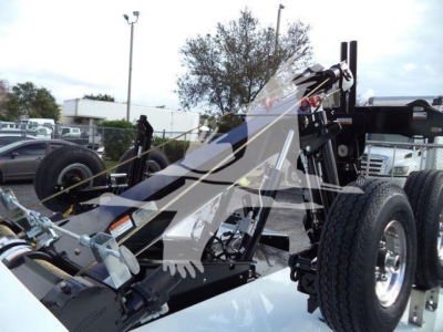 Truck wrecker chassis showing hydraulic winch assembly and dual rear tires, black frame with metal components.