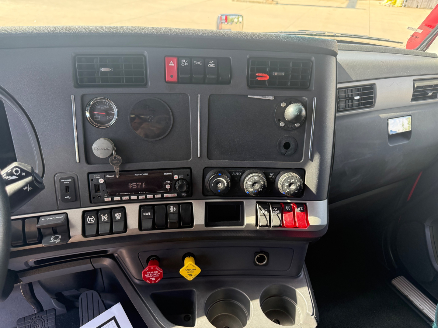 Dashboard and center console of a Kenworth T680 showing gauges, controls, and cup holders.