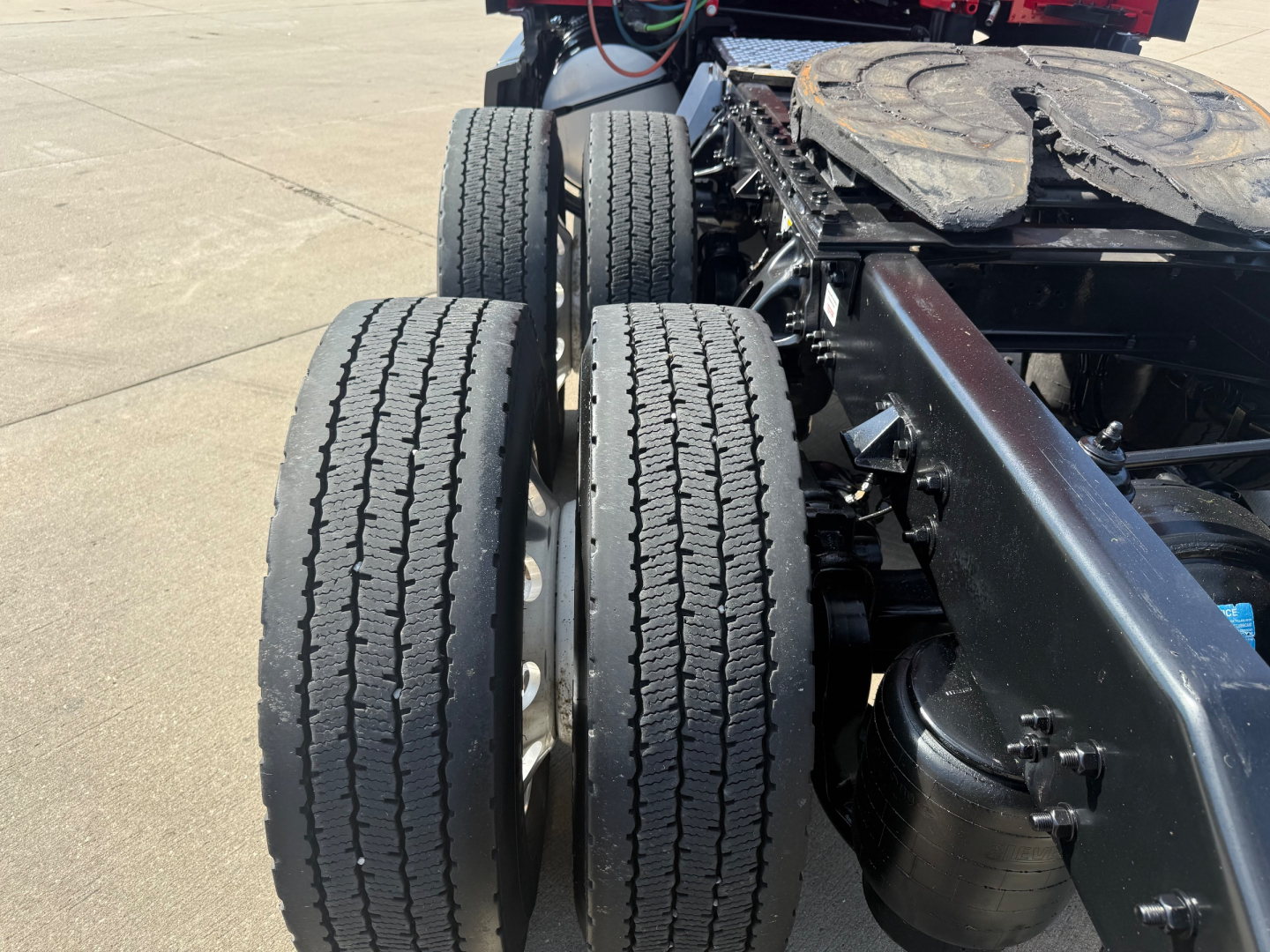 Kenworth T680 chassis with dual rear axles and tires visible, view of trailer connection area and spare tire on fifth wheel frame.
