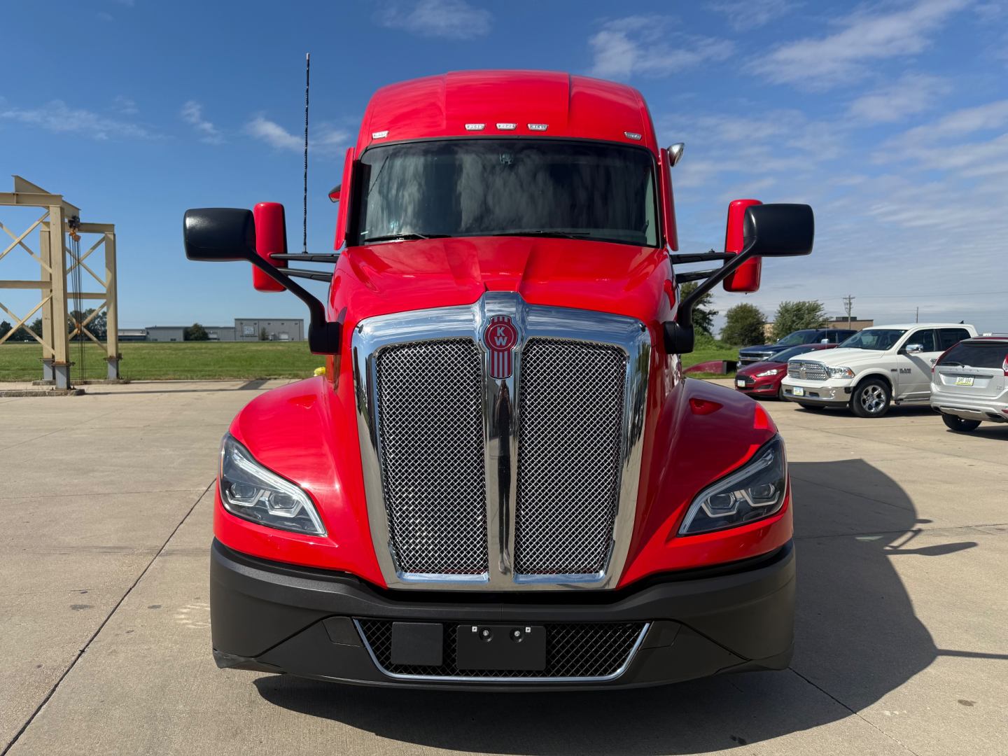 Front view of red 2023 Kenworth T680 conventional sleeper truck showing chrome grille, hood, and headlights.